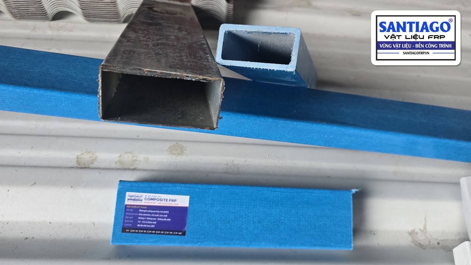 Hộp thép bị rỉ đặt cạnh thanh composite xanh